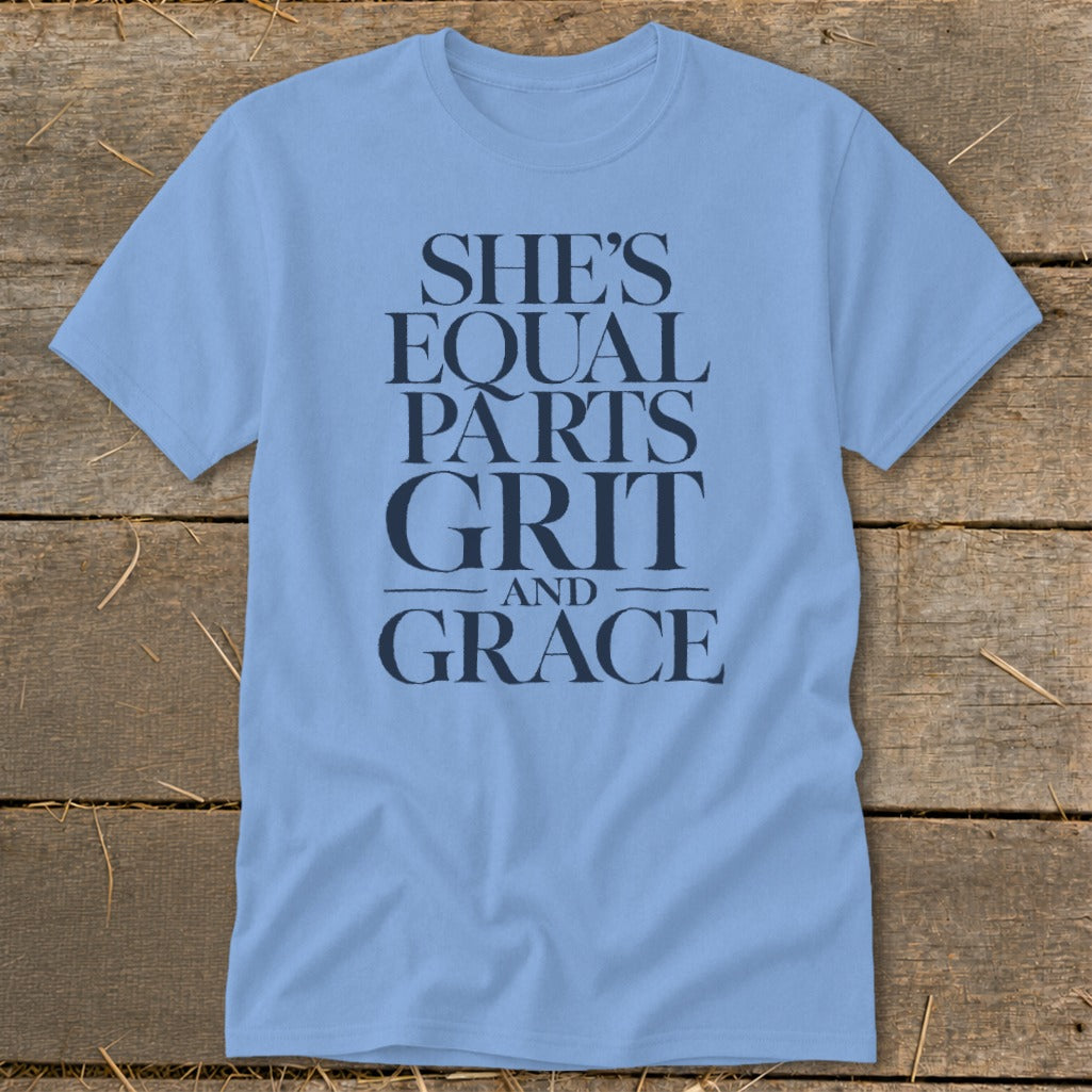 Light blue t-shirt with navy text: "SHE'S EQUAL PARTS GRIT AND GRACE".