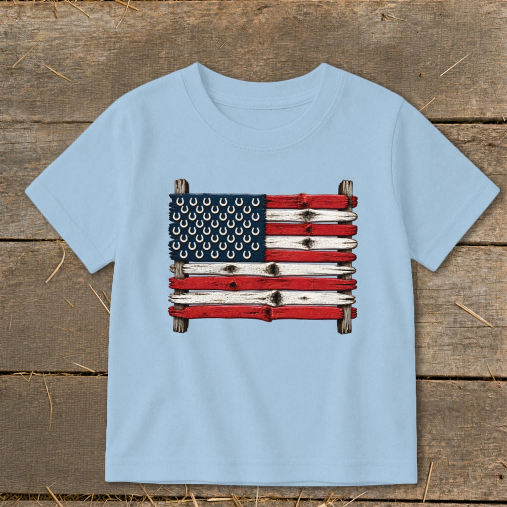 Light blue crewneck children's t-shirt featuring an American flag made of rustic wooden planks and horseshoes.