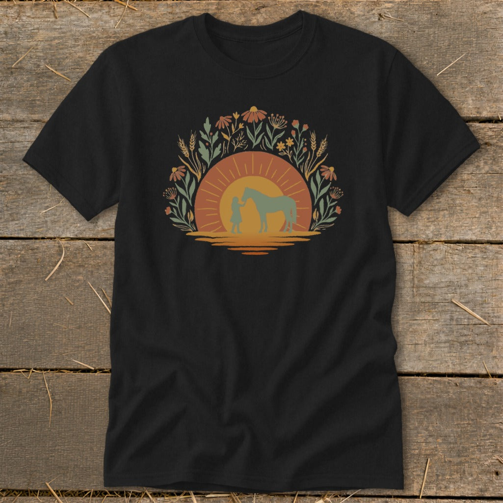 Black t-shirt with a graphic of a child and horse at sunset surrounded by flowers.