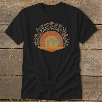 Black t-shirt with a graphic of a child and horse at sunset surrounded by flowers.