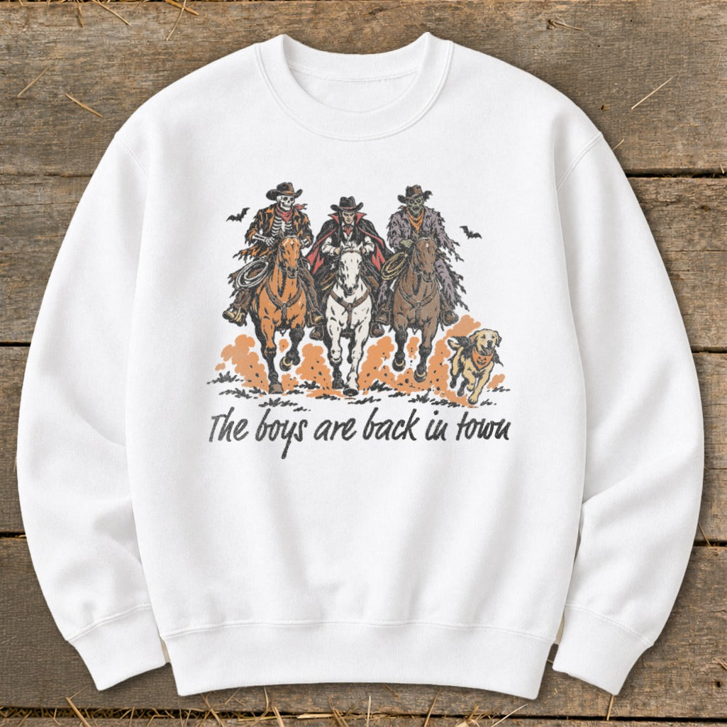 Three skeleton cowboys ride horses with a dog, text reads "The boys are back in town."