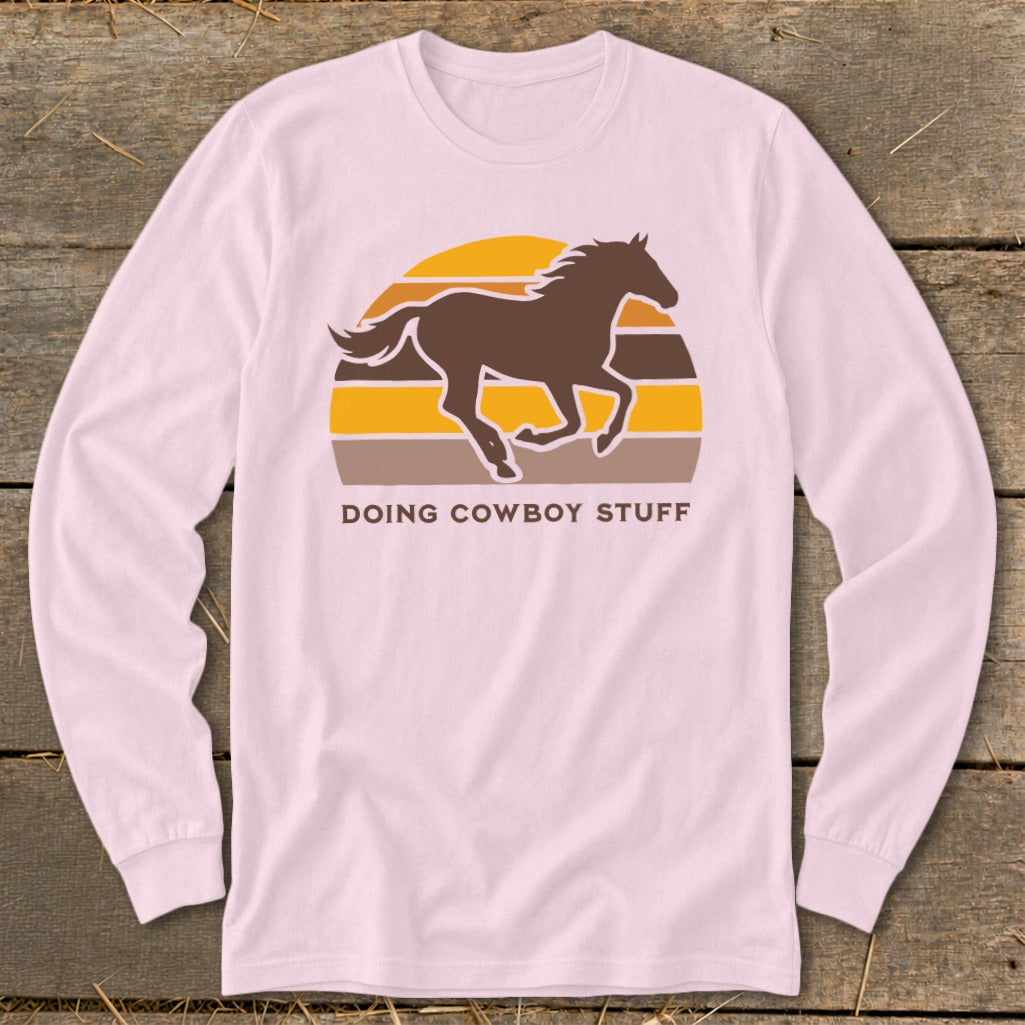 Pink long sleeve shirt with brown horse graphic and "DOING COWBOY STUFF" text.