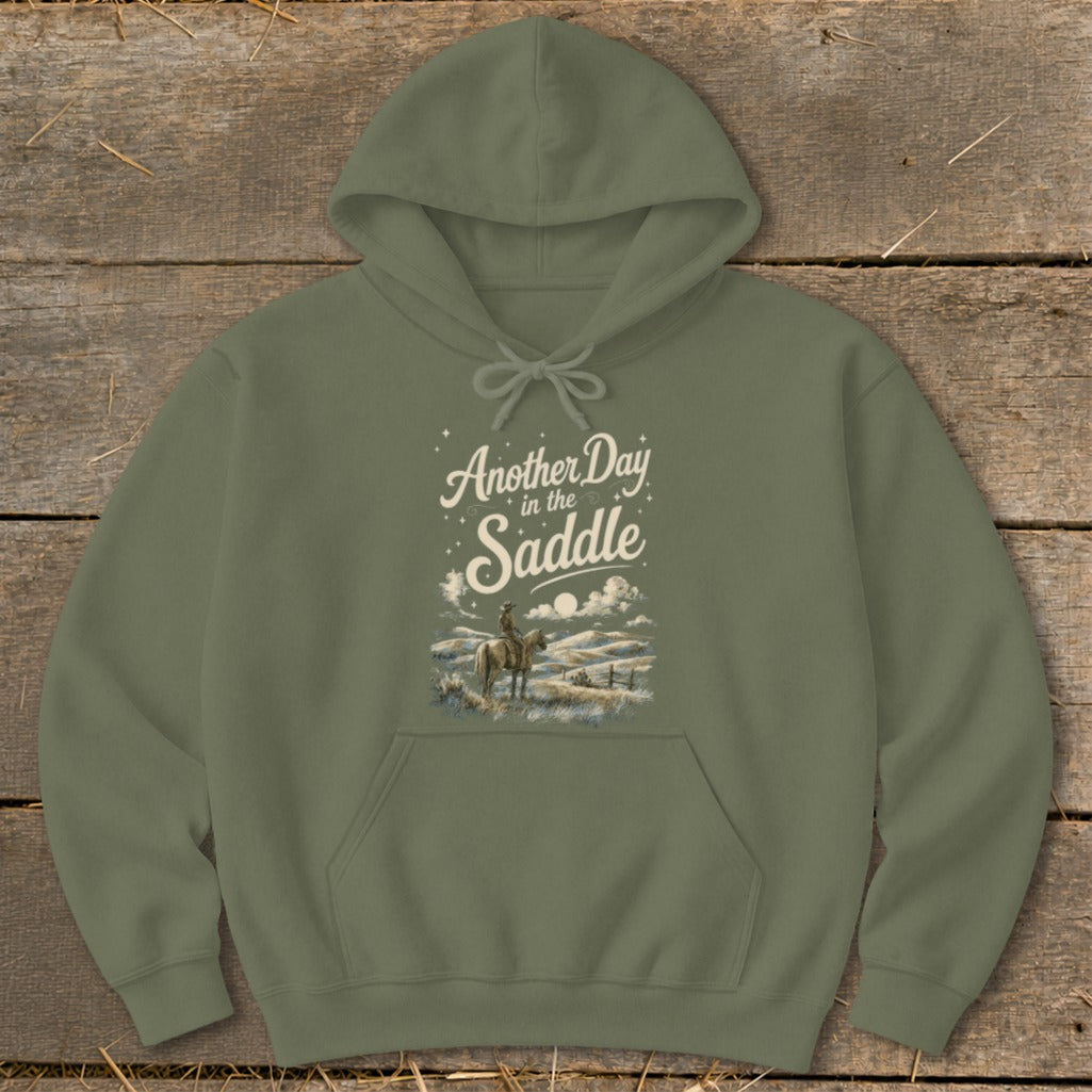 Olive hoodie with "Another Day in the Saddle" text and western landscape graphic.