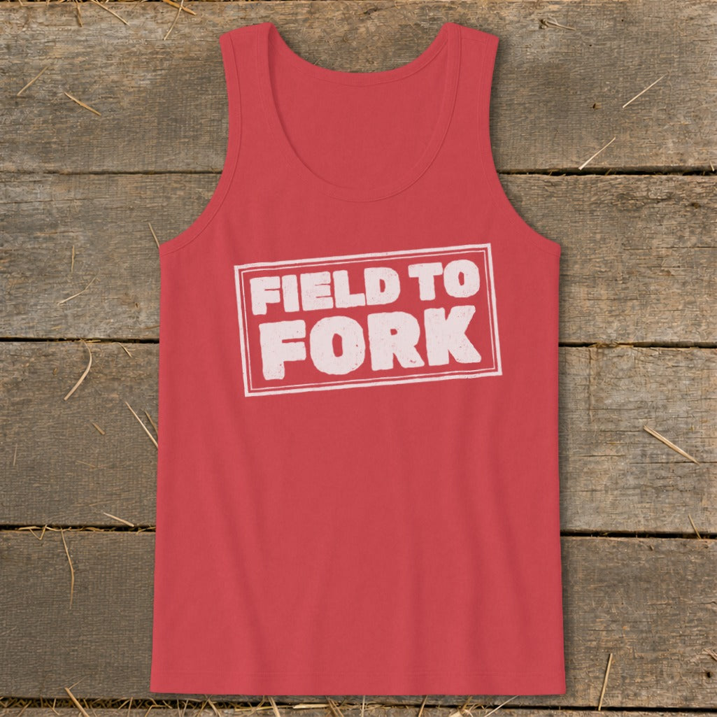 A red tank top featuring the white boxed text FIELD TO FORK laid on a rustic wooden background.
