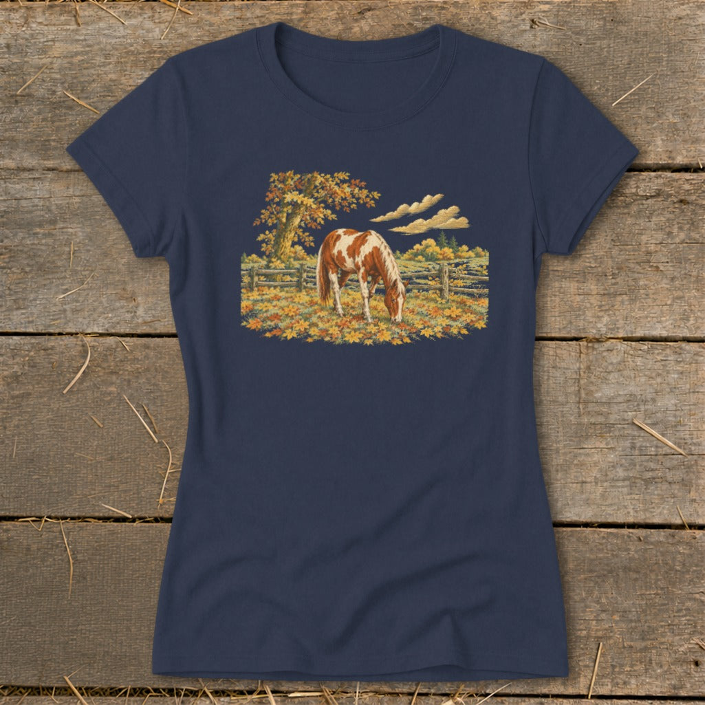 T-shirt with a brown and white horse grazing in a field of fallen autumn leaves.