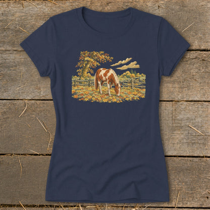 T-shirt with a brown and white horse grazing in a field of fallen autumn leaves.