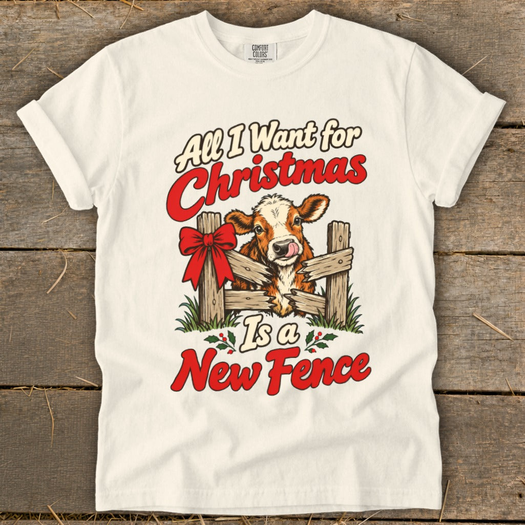 T-shirt graphic: cow with a red bow, leaning over a broken fence, "All I Want for Christmas Is a New Fence" text.