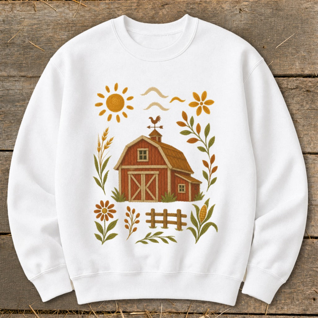 White sweatshirt with a barn, sun, flowers, and corn illustration.
