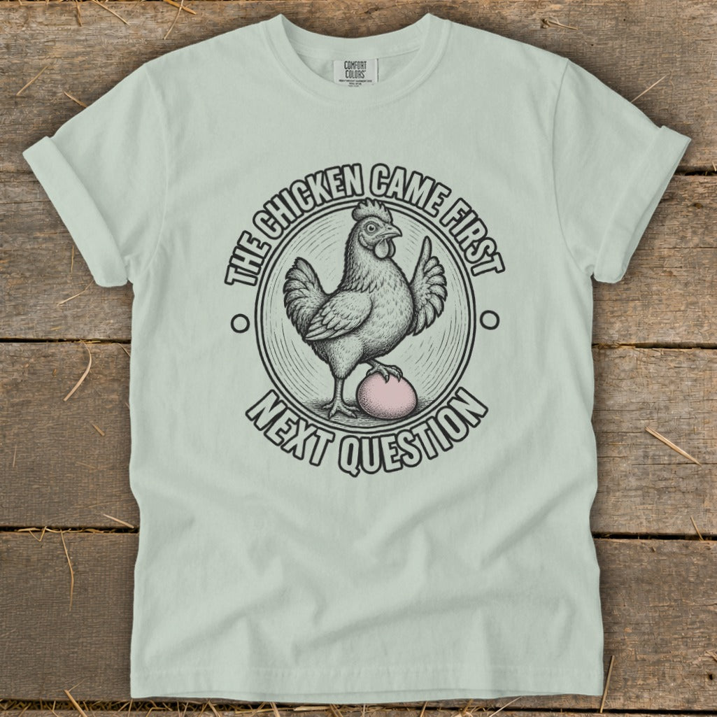 Light green t-shirt with a chicken and egg graphic and text.