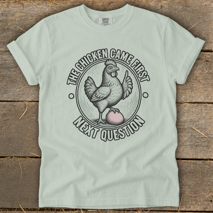 Light green t-shirt with a chicken and egg graphic and text.