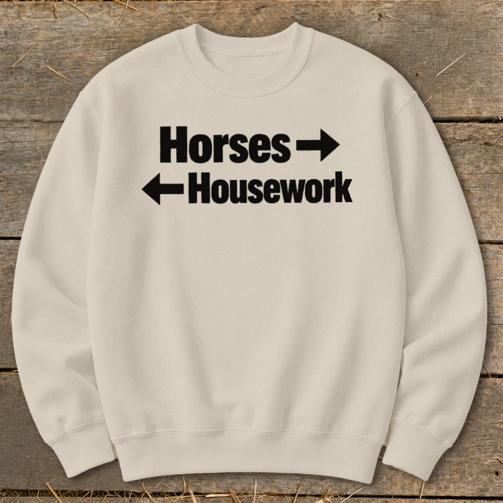 Cream-colored crewneck sweatshirt with black text reading Horses with a right arrow and Housework with a left arrow.