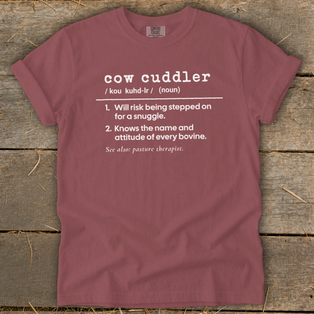 A dusty rose crewneck t-shirt featuring humorous white text defining a cow cuddler.