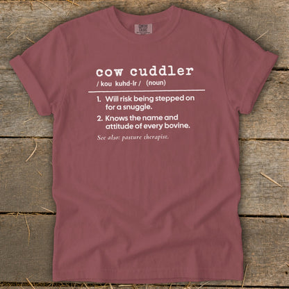 A dusty rose crewneck t-shirt featuring humorous white text defining a cow cuddler.