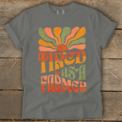 Grey t-shirt with "TIRED AS A FARMER" in retro font and colors.