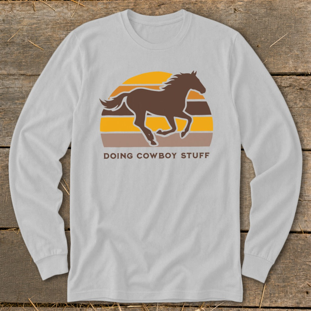 Brown horse silhouette galloping against striped sunset, "Doing Cowboy Stuff" text.