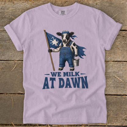 Cow in overalls holding a flag and bucket with text "WE MILK AT DAWN".