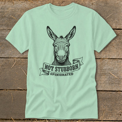 Light green t-shirt with black sketch of a donkey head above a banner saying "NOT STUBBORN OPINIONATED".