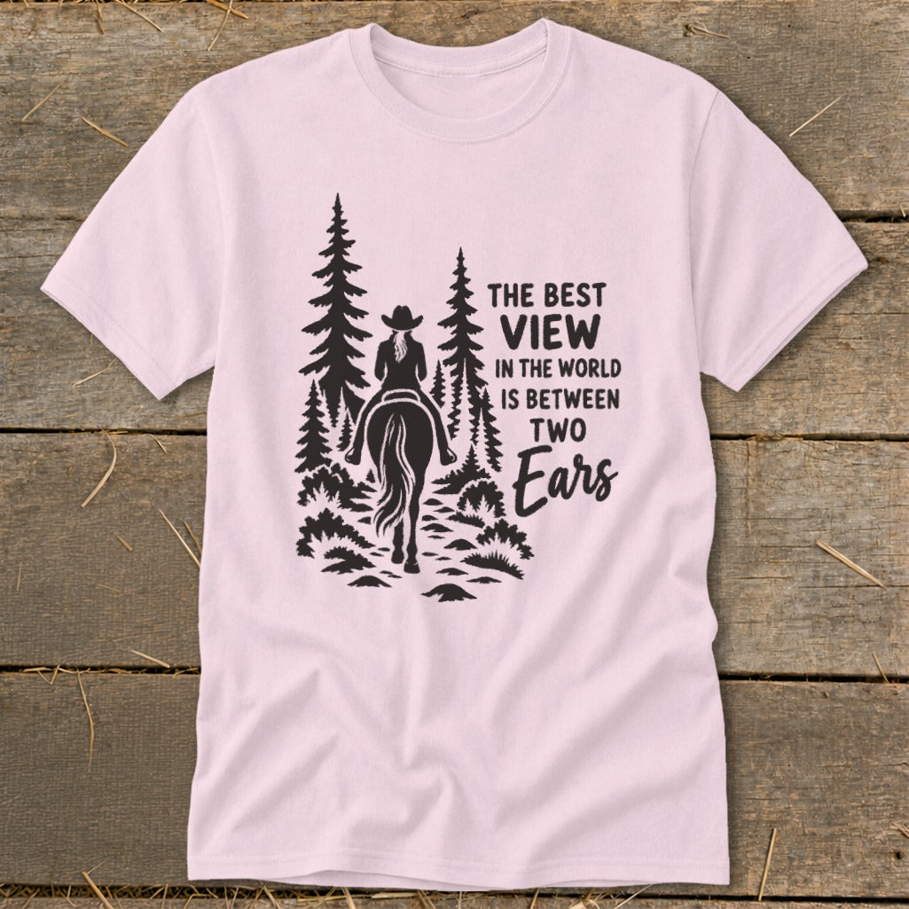 A light pink t-shirt printed with a silhouette of a horseback rider and text reading The Best View In The World Is Between Two Ears.