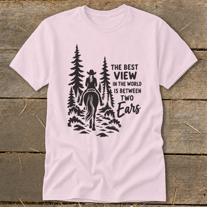 A light pink t-shirt printed with a silhouette of a horseback rider and text reading The Best View In The World Is Between Two Ears.
