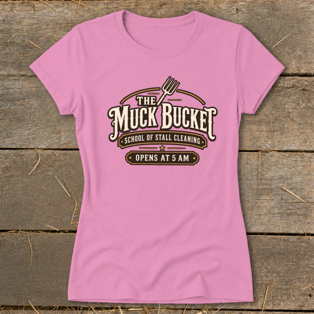 Pink t-shirt with "The Muck Bucket School of Stall Cleaning Opens at 5 AM" logo.