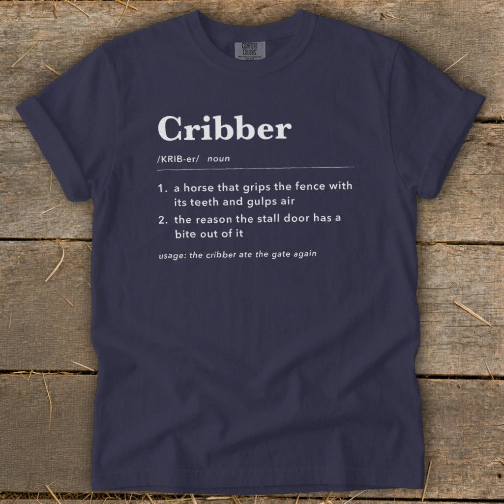 Dark blue t-shirt featuring white text that humorously defines the word cribber as a horse behavior.