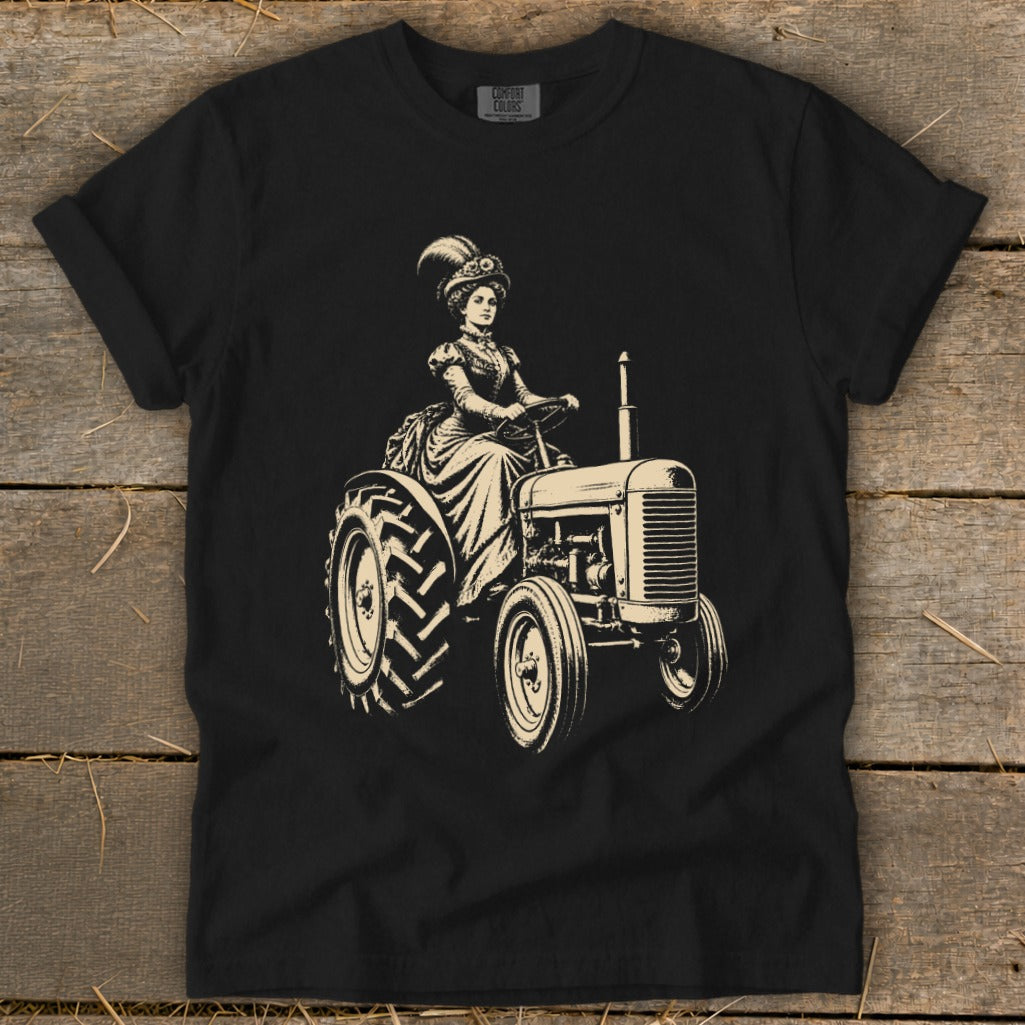Black t-shirt with a sepia illustration of a woman in Victorian attire driving a tractor.