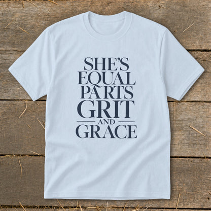 Light blue t-shirt with navy text that reads "SHE'S EQUAL PARTS GRIT AND GRACE".