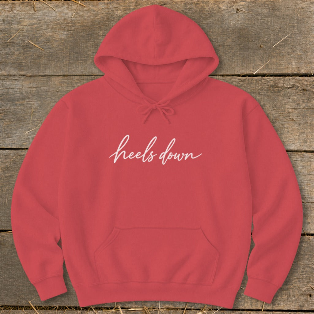 Red hoodie with "heels down" text on a wooden background.