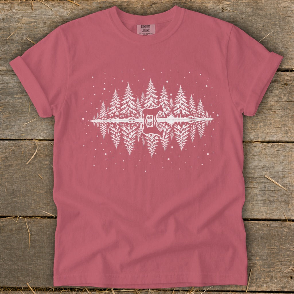 Pink t-shirt with a white graphic of pine trees and a deer silhouette reflected in water.