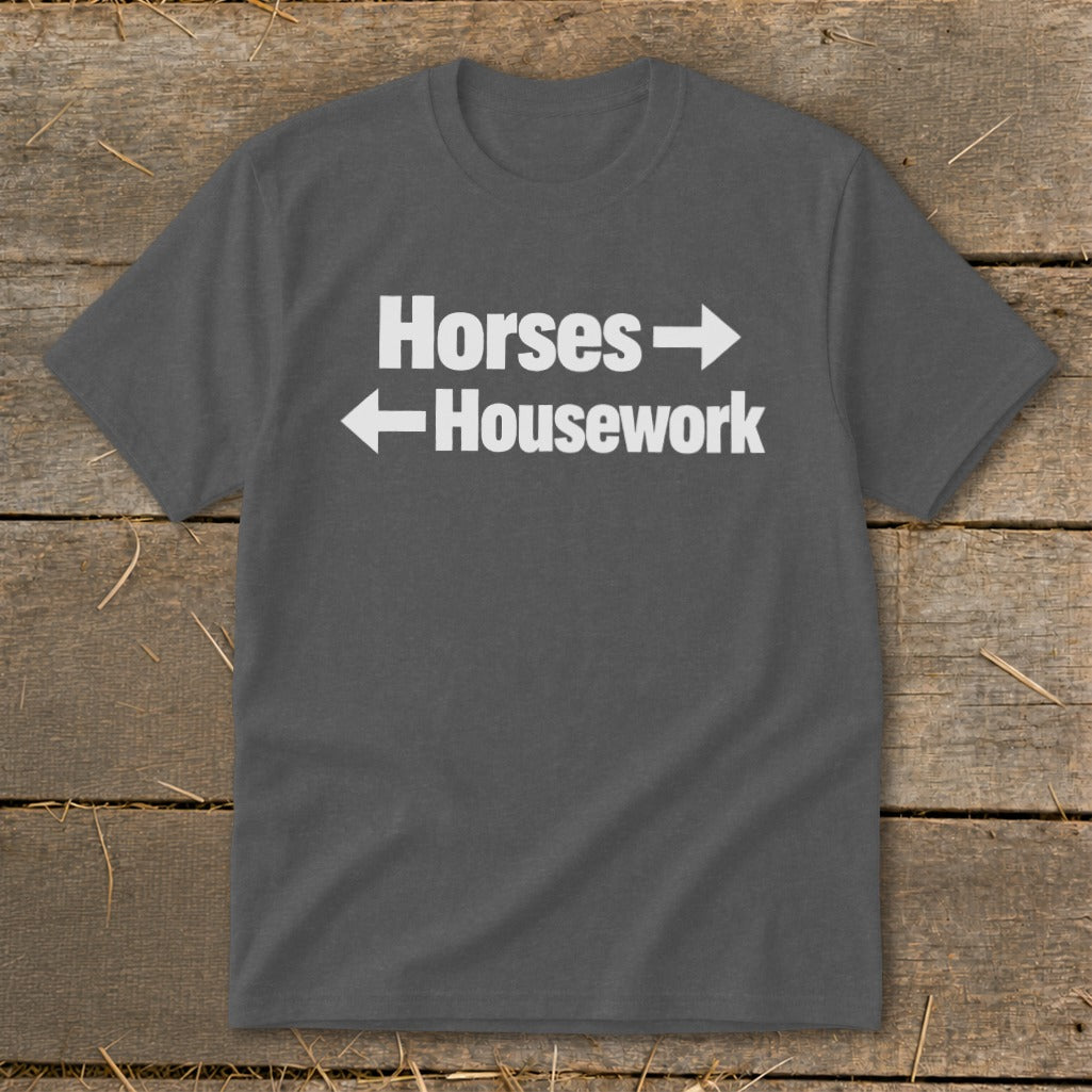 A dark gray t-shirt with white text reading Horses and Housework, separated by directional arrows.