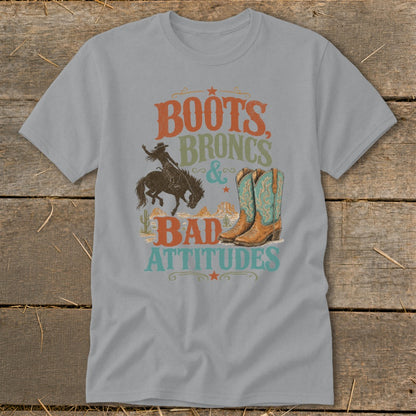 Gray t-shirt with "Boots, Broncs & Bad Attitudes" text, bucking bronco, and cowboy boots graphic.