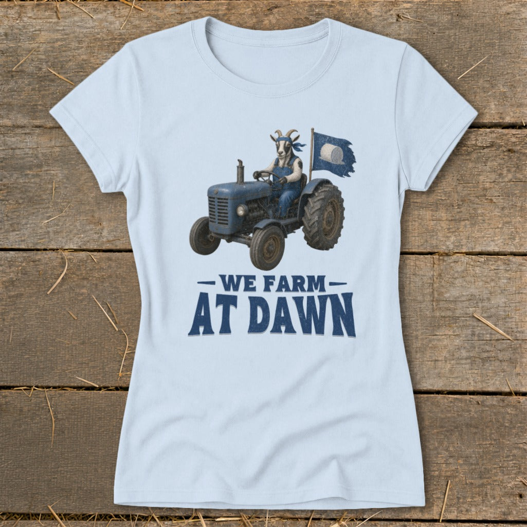 Light blue t-shirt with a goat driving a blue tractor and a flag that reads "We Farm At Dawn".