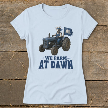 Light blue t-shirt with a goat driving a blue tractor and a flag that reads "We Farm At Dawn".