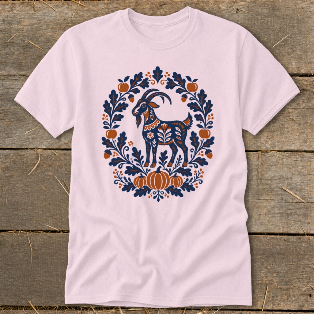 Light pink t-shirt featuring a folk art graphic of a goat surrounded by leaves, acorns, and pumpkins.