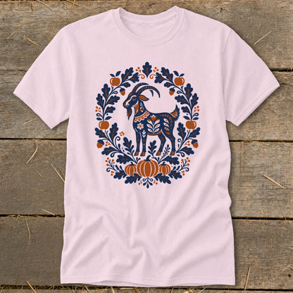 Light pink t-shirt featuring a folk art graphic of a goat surrounded by leaves, acorns, and pumpkins.