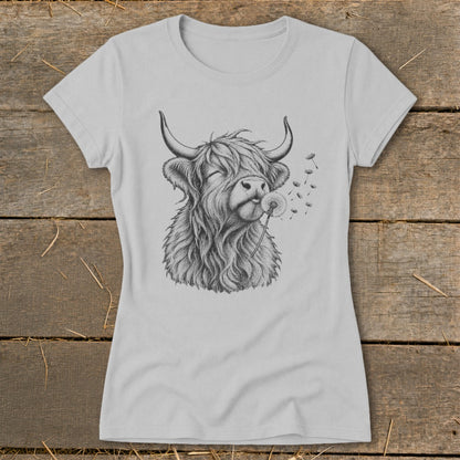 T-shirt graphic of a Highland cow blowing on a dandelion.