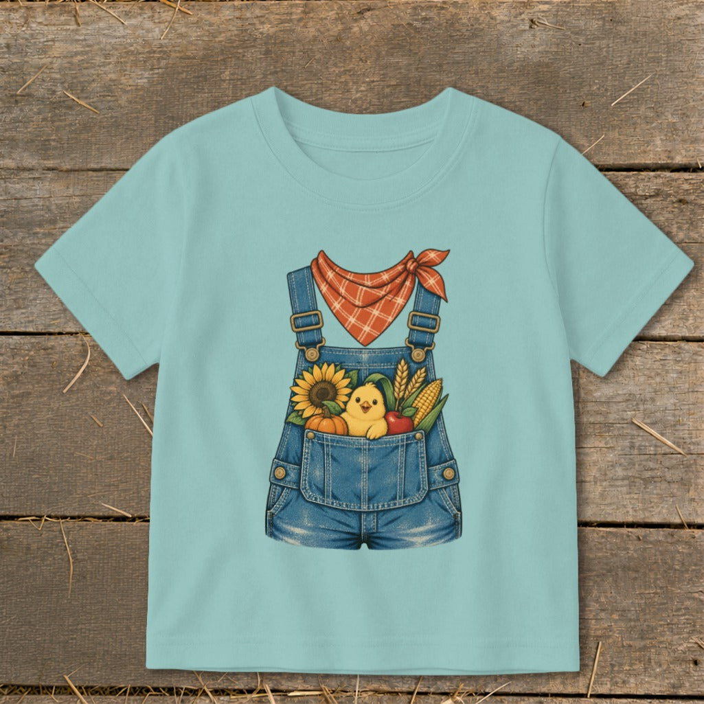 Light blue t-shirt with a denim overalls graphic featuring a chick, sunflower, pumpkin, and corn.