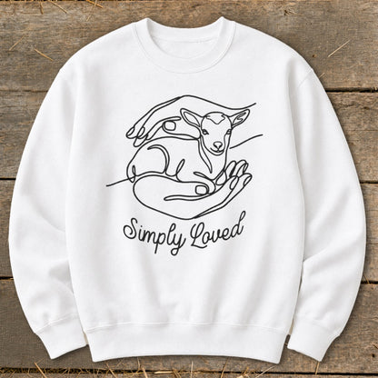 White sweatshirt with line art of hands holding a lamb and text "Simply Loved".