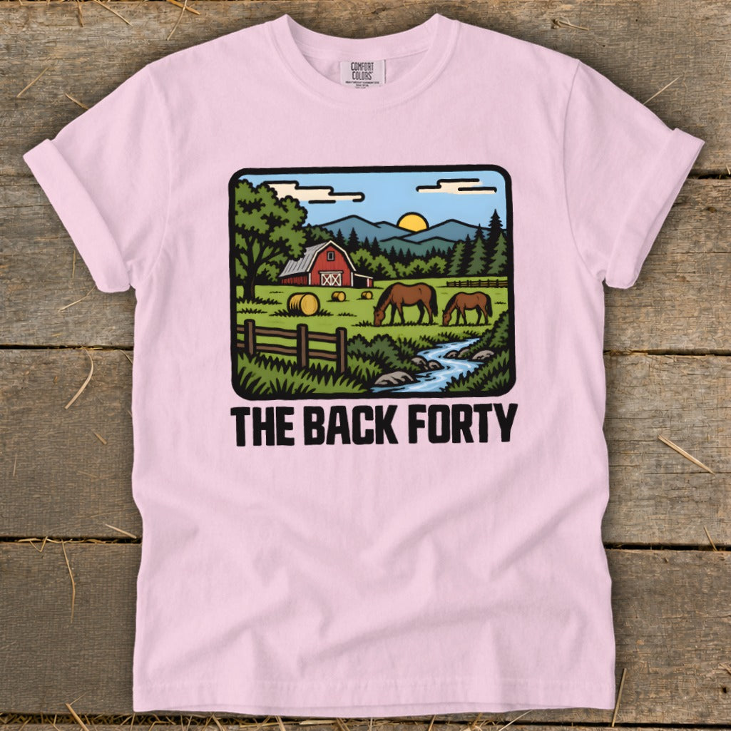 A light pink crewneck t-shirt featuring a pastoral farm illustration and the text The Back Forty.