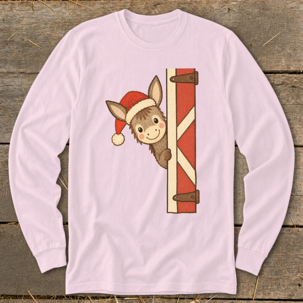 Donkey wearing Santa hat peeking from behind barn door on pink long-sleeve shirt.