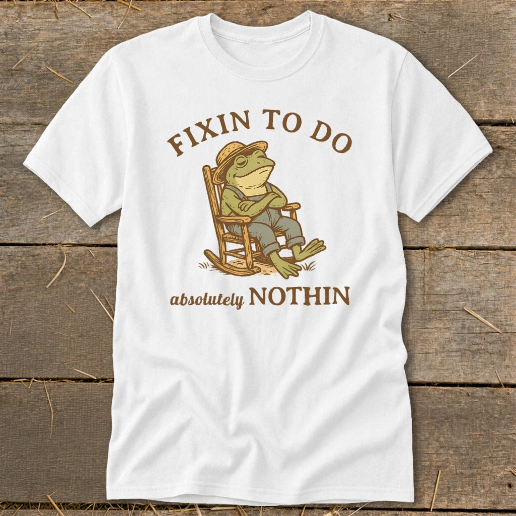 White t-shirt with graphic of frog in rocking chair and text "Fixin to do absolutely nothin".