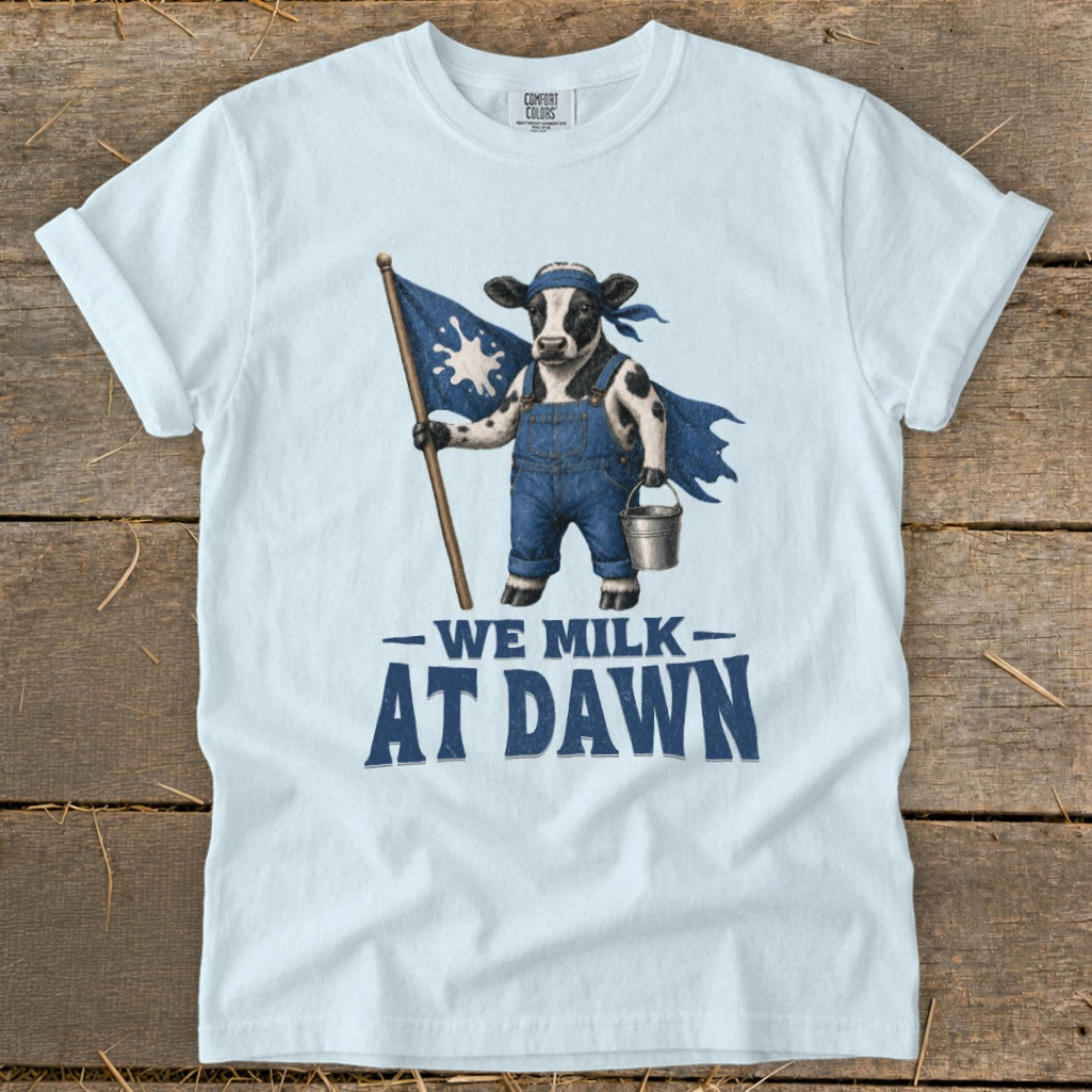 Cow in overalls and cape holding flag, carrying bucket, text "We Milk At Dawn."