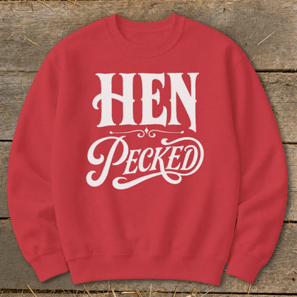 Red sweatshirt with white text that reads "HEN Pecked" on a wooden background.