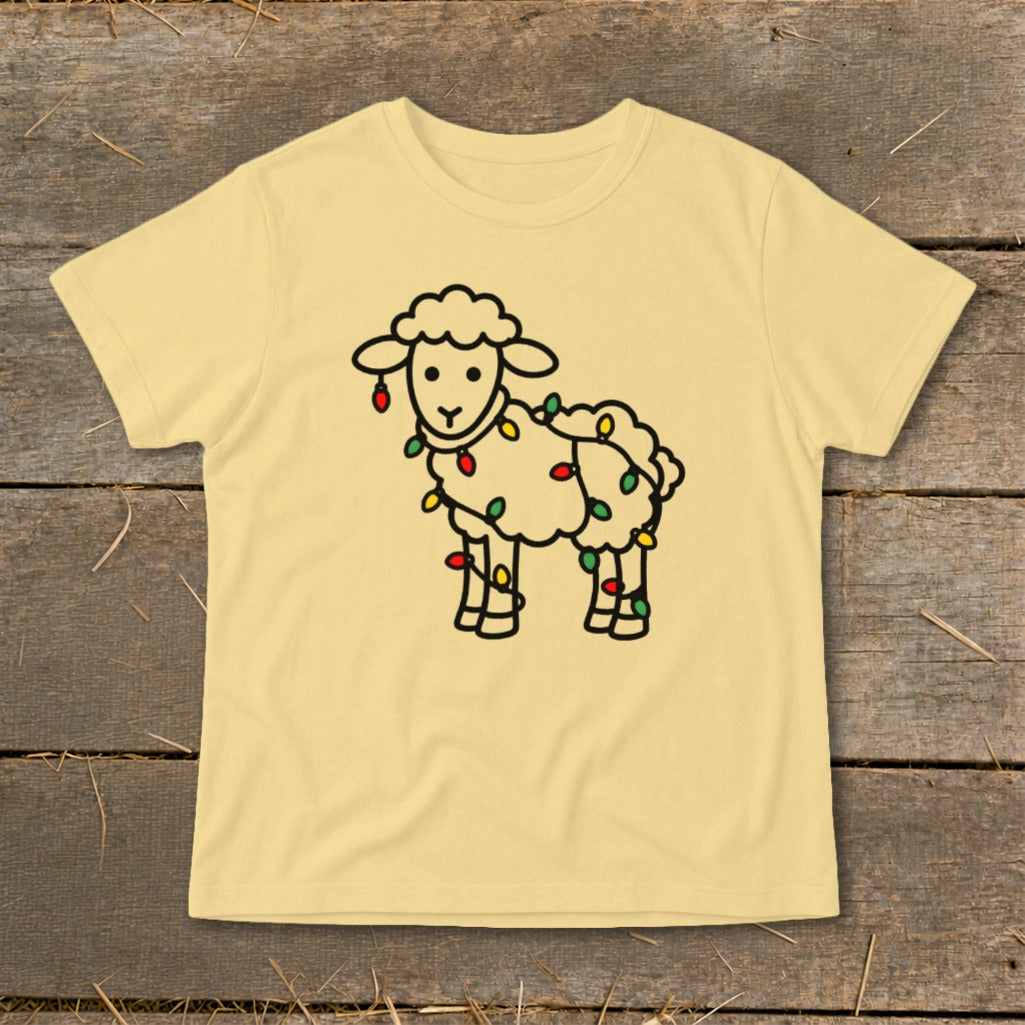 A pale yellow short-sleeved t-shirt features a cartoon outline of a sheep wrapped in colorful Christmas lights.