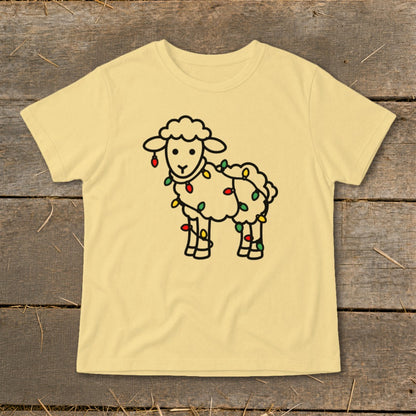 A pale yellow short-sleeved t-shirt features a cartoon outline of a sheep wrapped in colorful Christmas lights.