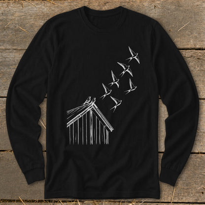 A black long-sleeve t-shirt with a white line art graphic of birds flying from a rustic wooden barn.