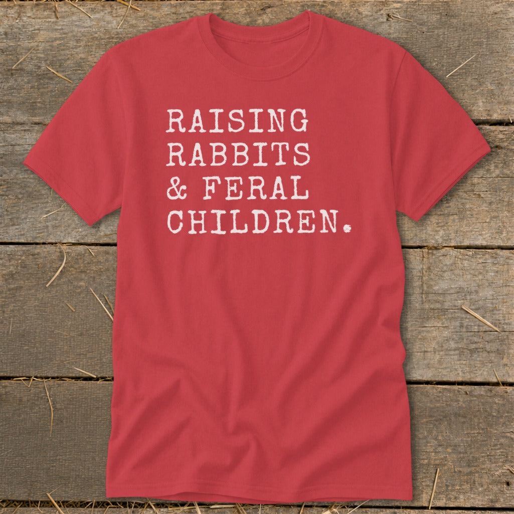 Red t-shirt with white text: "RAISING RABBITS & FERAL CHILDREN."
