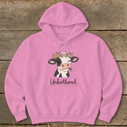 Pink hoodie with a black and white cow wearing a flower crown and eating grass, text says "Unbothered".