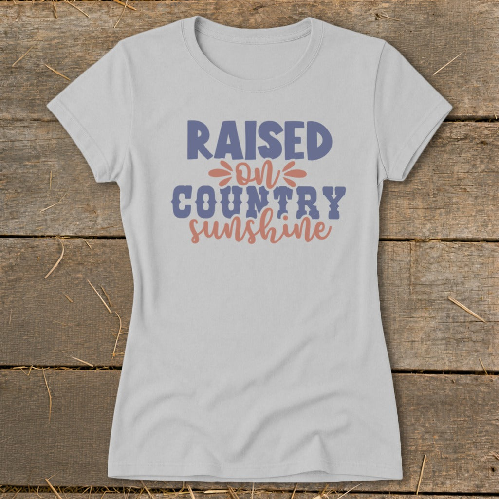 Light gray t-shirt with "Raised On Country Sunshine" graphic in blue and coral.