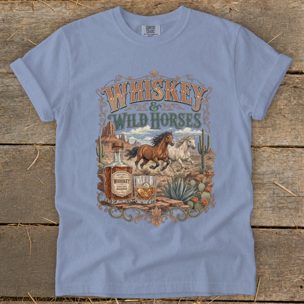 Whiskey & Wild Horses t-shirt graphic with desert scene, horses, whiskey bottle, and rocks glass.
